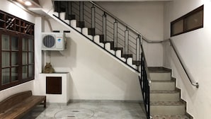 A staircase with a handrail, a bench, and an air conditioning unit mounted on the wall. - RedDoorz near XT Square 3 (Yogyakarta)