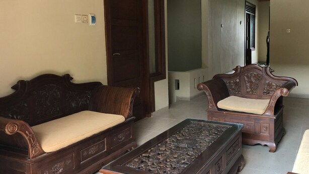 A room with two wooden sofas and a matching wooden coffee table. - RedDoorz near XT Square 3 (Yogyakarta)