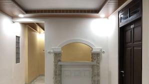 A hallway with a stone fireplace, a door, and a light fixture on the ceiling. - RedDoorz near XT Square 3 (Yogyakarta)