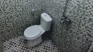 A bathroom with a toilet, a shower, and a wall-mounted heater. - RedDoorz near Exit Toll Jatiwarna 2 (Bekasi)