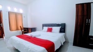 A hotel room with a bed, a desk, and a wardrobe. - RedDoorz near Exit Toll Jatiwarna 2 (Bekasi)