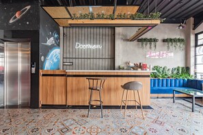A modern bar area with a wooden counter, two stools, and a neon sign reading "sleep is love". - RedDoorz Plus @ Doorman Guest House (Bandung)