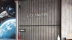 A room with a space-themed mural, a wooden slatted wall, and the name 'Doorman' on the wall. - RedDoorz Plus @ Doorman Guest House (Bandung)
