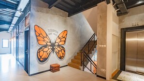 A modern interior with a large butterfly mural, a staircase, and an elevator. - RedDoorz Plus @ Doorman Guest House (Bandung)