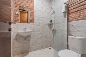 A bathroom with a white sink, a glass shower enclosure, and a toilet. - RedDoorz Plus @ Doorman Guest House (Bandung)