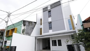 A modern two-story house with a white facade, a garage, and a small courtyard. - RedDoorz Plus Syariah near Mall Pondok Indah (Jakarta)