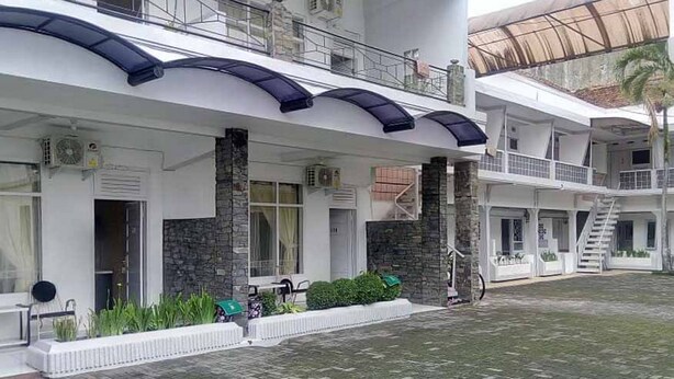 A multi-story hotel with a covered outdoor area, stone pillars, and a staircase. - RedDoorz Syariah @ Hotel Kencana Tasikmalaya (Tasikmalaya)