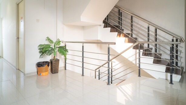 A modern interior with a staircase, a trash bin, and a potted plant. - Sans Hotel Kupang Indah Surabaya (Surabaya)