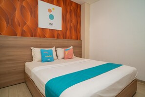 A neatly made bed with a white and teal bedspread, a wooden headboard, and colorful pillows.