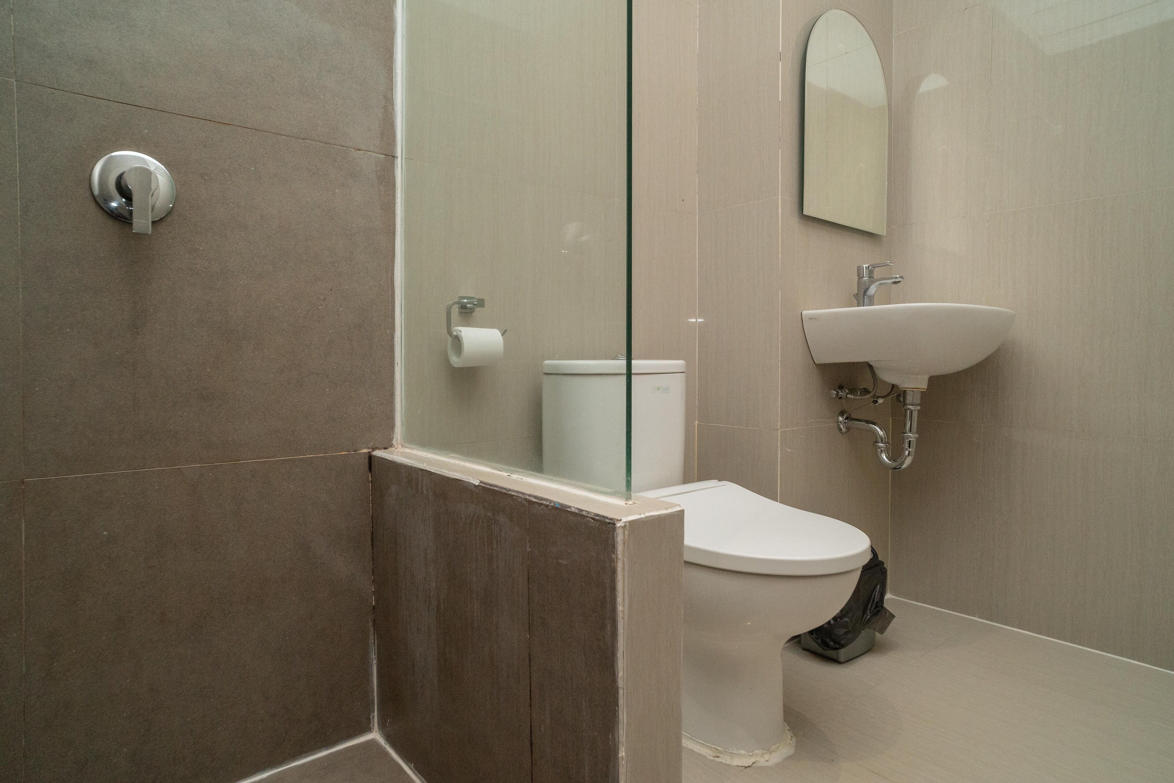 Une salle de bain moderne avec une douche à parois de verre, des toilettes blanches et un lavabo avec un miroir au-dessus.