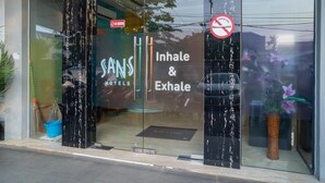 A hotel entrance with a sign reading "SANS HOTELS" and "Inhale & Exhale". - Sans Hotel Kupang Indah Surabaya (Surabaya)