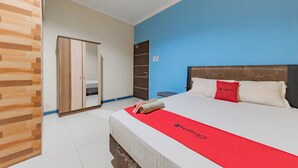 A hotel room with a bed, a wardrobe, and a blue wall.