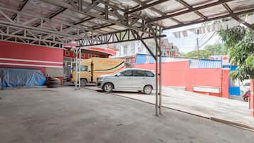 Un área de estacionamiento techada con piso de concreto, una camioneta amarilla y un auto plateado.
