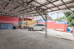 Un espace de stationnement couvert avec un sol en béton, un camion jaune et une voiture argentée.
