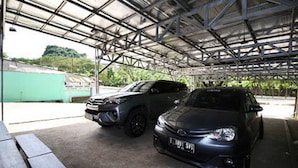 A covered parking area with two cars parked under a metal roof.