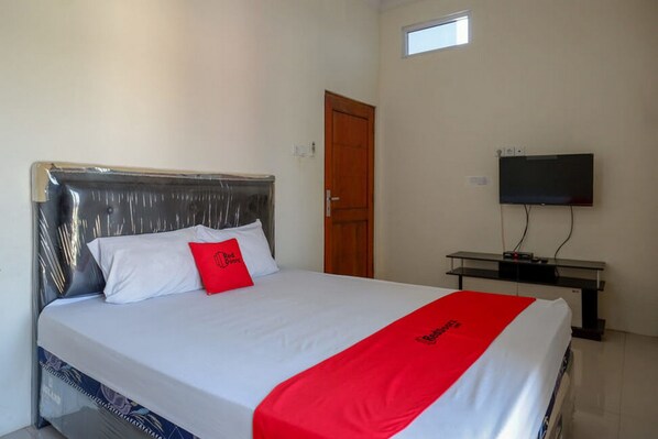 Una habitación de hotel con una cama, televisión y puerta de madera.
