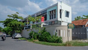Een modern gebouw met een plat dak, grote ramen en een naambord.