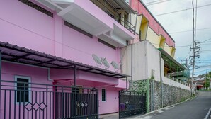 Ein pinkfarbenes Gebäude mit einem vergitterten Eingang, Satellitenschüsseln und einer Steinmauer.