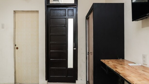 Um quarto com uma mesa de madeira, um armário preto e uma porta bege.