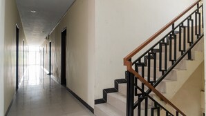 Um corredor comprido e estreito com uma escada à direita.