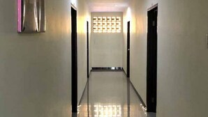 Um corredor com piso refletivo, portas em ambos os lados e uma parede estampada no final.