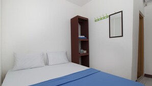 A bedroom with a bed, a brown wardrobe, a mirror, and a green coat rack. - RedDoorz near Riau Junction Mall 2 (Bandung)