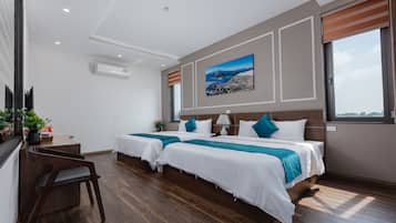 A hotel room with two beds, a desk, and a large window.