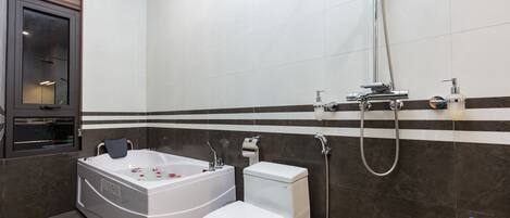 A modern bathroom with a bathtub, toilet, and shower.