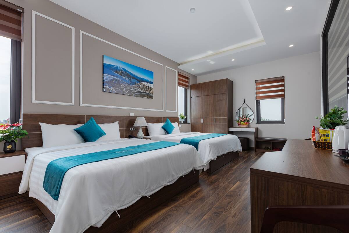 A modern hotel room with two beds, a desk, and a large window.