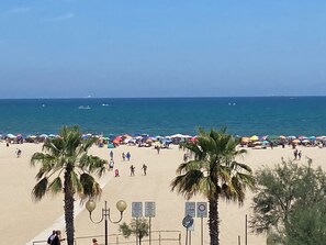 Una playa con palmeras, sombrillas y gente.