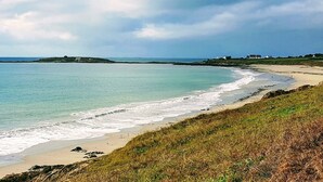 A coastal landscape with a sandy beach, calm sea, and grassy areas. - Ty Kergui - Villa 400m from Tahiti sand beach (Névez)