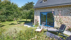 A stone house with a blue door, a small window, and a garden with chairs and flowers. - Ty Kergui - Villa 400m from Tahiti sand beach (Névez)