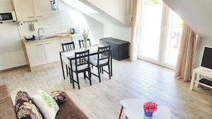 A modern kitchen with white cabinets, a dining area with a table and chairs, and a cozy living space with a sofa. - Adriatic Pearl Korcula (Korcula)