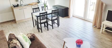 A modern kitchen with white cabinets, a dining area with a table and chairs, and a cozy living space with a sofa.