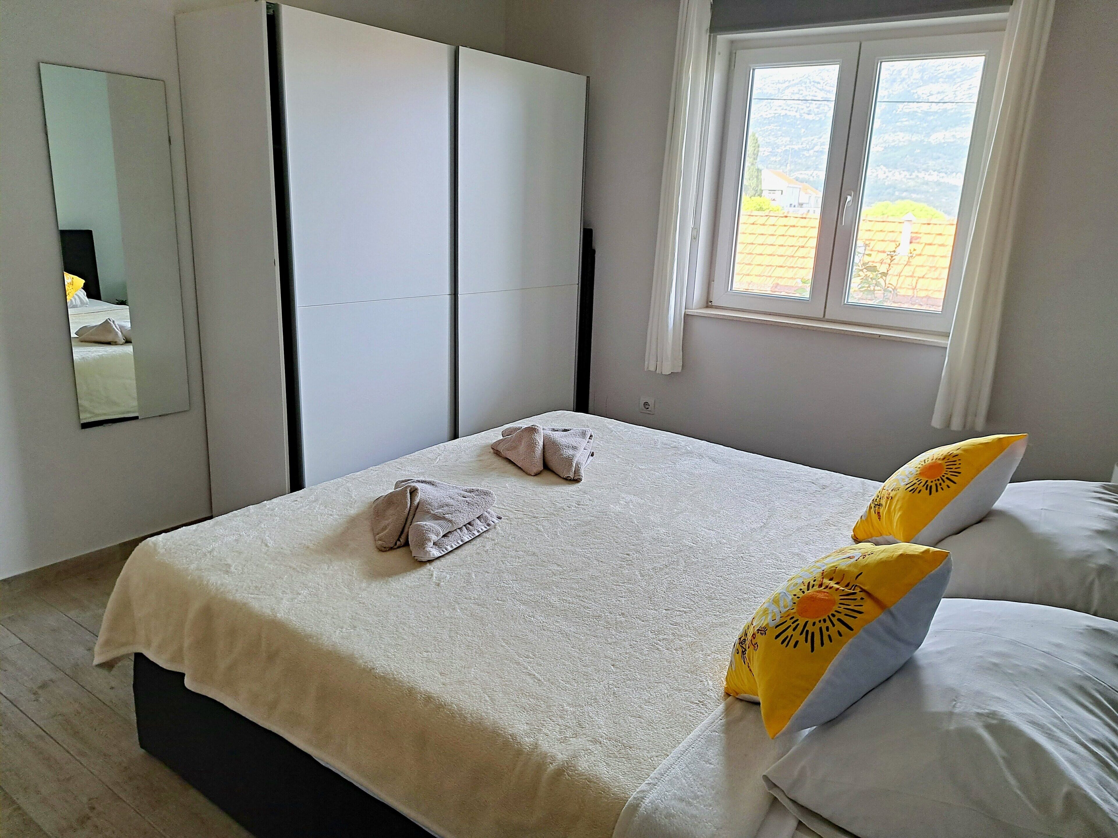 Une chambre à coucher avec un lit, une armoire, une fenêtre et un miroir.