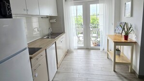 A modern kitchen with white cabinets, a built-in oven, and a dining area with a table and chairs. - Adriatic Pearl Korcula (Korcula)
