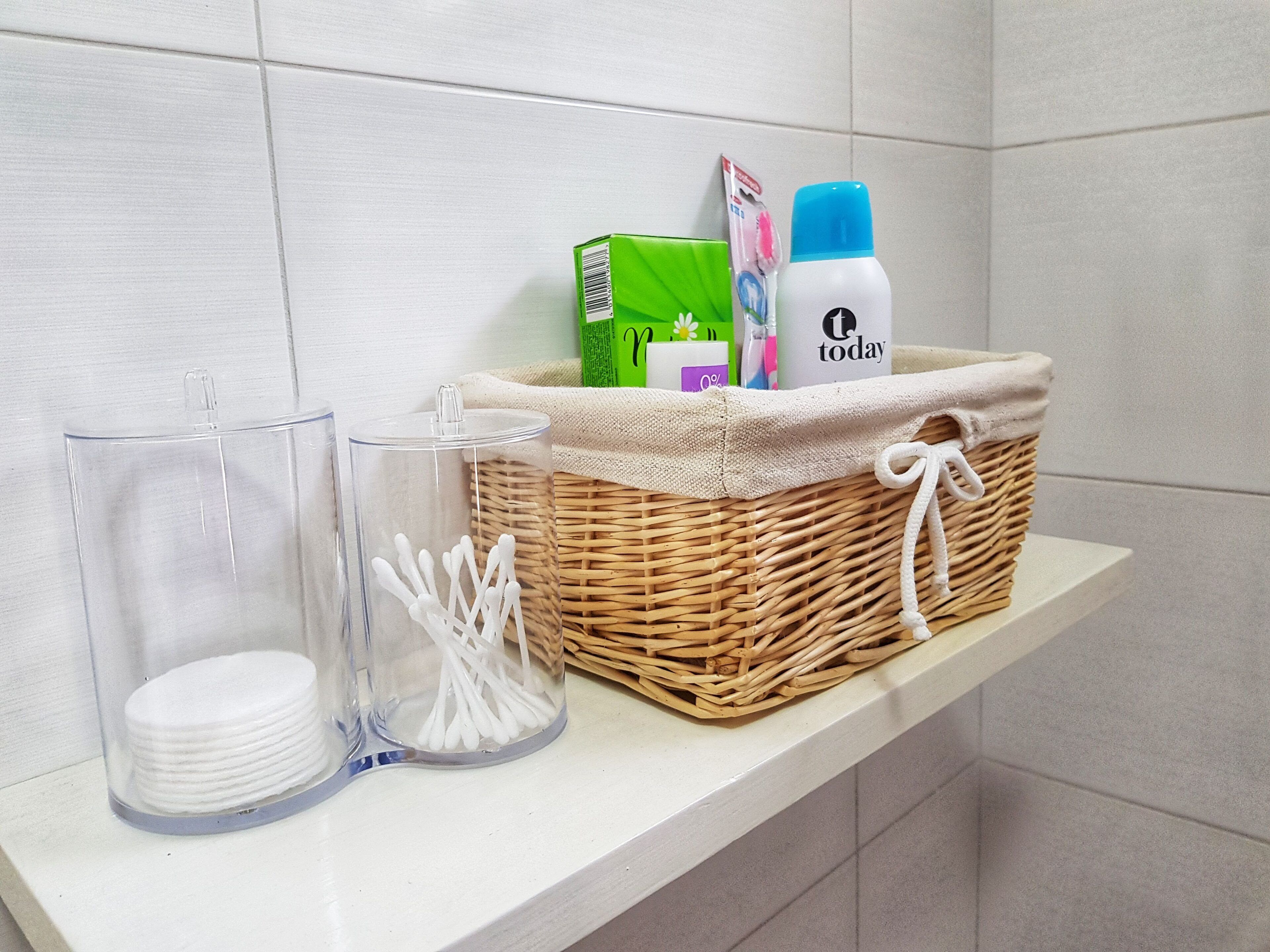Une étagère de salle de bain avec un panier en osier contenant une brosse à dents, du dentifrice et une petite boîte.