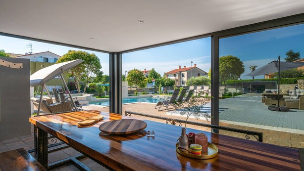 A modern kitchen with a large window overlooking a pool and outdoor seating area. - Villa Zorica in Poreč with 7 Bedrooms, Pool, Fireplace (Poreč)