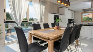 A modern dining area with a wooden table, black chairs, and a view of a swimming pool. - Villa Zorica in Poreč with 7 Bedrooms, Pool, Fireplace (Poreč)