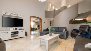 A modern living room with a flat-screen TV, a sofa, a coffee table, and a staircase. - Villa Zorica in Poreč with 7 Bedrooms, Pool, Fireplace (Poreč)