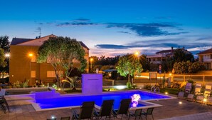A swimming pool with lounge chairs and a water feature, surrounded by buildings and trees. - Villa Zorica in Poreč with 7 Bedrooms, Pool, Fireplace (Poreč)