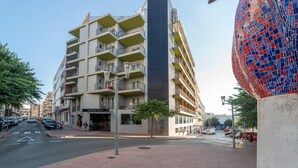 A multi-story building with balconies, a street view, and a mosaic sculpture. - ARTIEM Urban Apartments (Mahón)