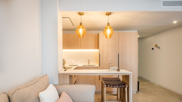 A modern kitchen with pendant lighting, a wooden dining table, and a bar stool. - ARTIEM Urban Apartments (Mahón)