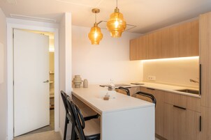 Una cocina moderna con una isla central, iluminación colgante y armarios de madera.