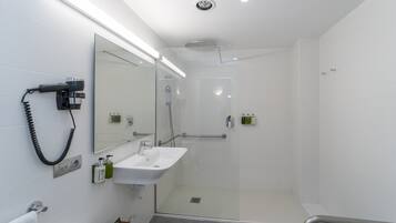 Une salle de bain moderne avec une douche à parois de verre, un lavabo blanc et un sèche-cheveux fixé au mur.