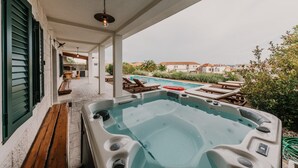 A hot tub in a covered outdoor area with a pool in the background. - Mix of modern and antique , New visage villa Antico (Seget Donji)