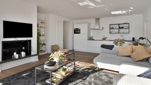A modern living room with a flat-screen TV, a glass coffee table, and a grey sofa with beige cushions. - Luxurious Penthouse, rooftop terrace, spectacular view! (Antwerpen)