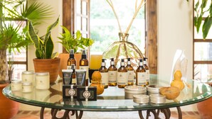 A glass table with various products, including candles, bottles, and a decorative item. - Casa Ritual (Puerto Vallarta)