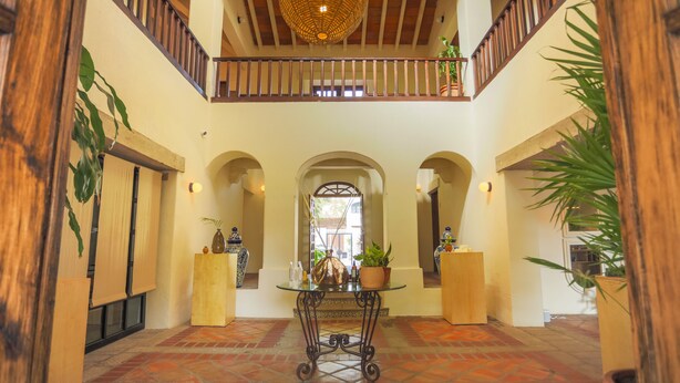 A spacious lobby with a high ceiling, a central table with potted plants, and a staircase leading to an upper level. - Casa Ritual (Puerto Vallarta)