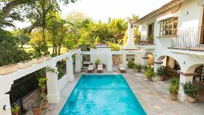 A pool area with a rectangular pool, lounge chairs, and potted plants. - Casa Ritual (Puerto Vallarta)
